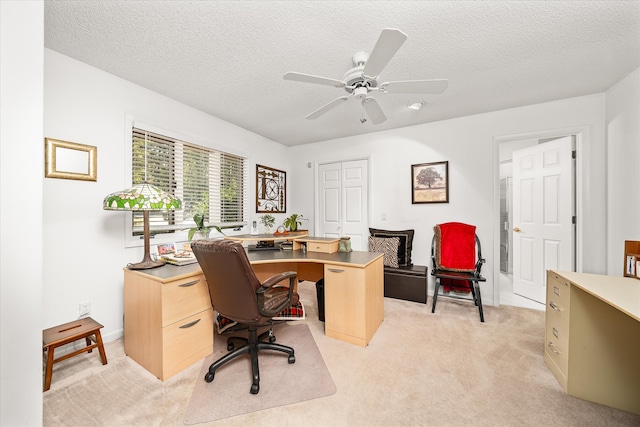 carpeted home office with a textured ceiling and ceiling fan