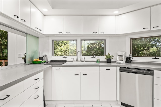 kitchen featuring dishwasher, sink, light tile patterned floors, and white cabinetry