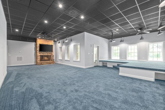 unfurnished living room with ceiling fan, a fireplace, and carpet floors