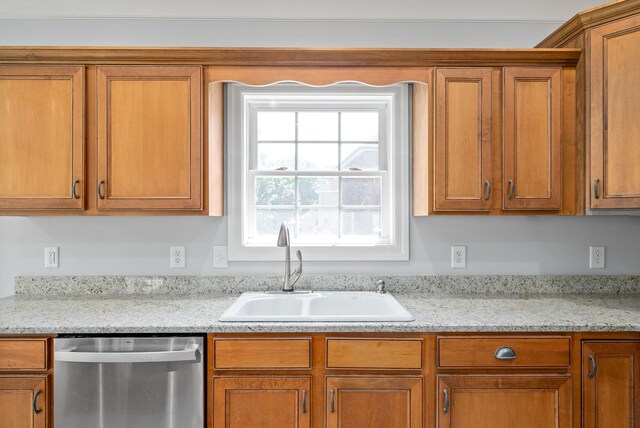 kitchen featuring stainless steel dishwasher, light stone counters, and sink