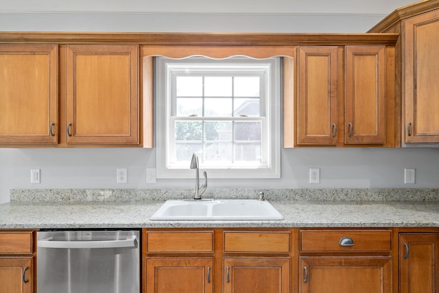 kitchen with dishwasher, brown cabinetry, and a sink