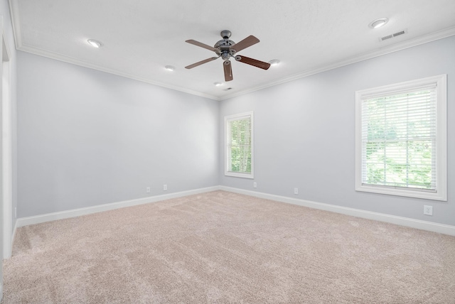 carpeted empty room featuring baseboards, visible vents, a ceiling fan, and ornamental molding