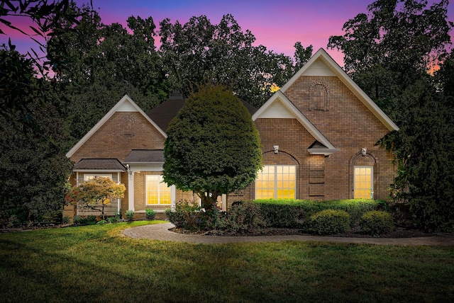 view of front of property with brick siding and a yard