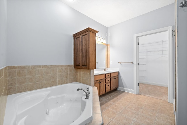 bathroom with baseboards, a jetted tub, tile patterned flooring, a walk in closet, and vanity