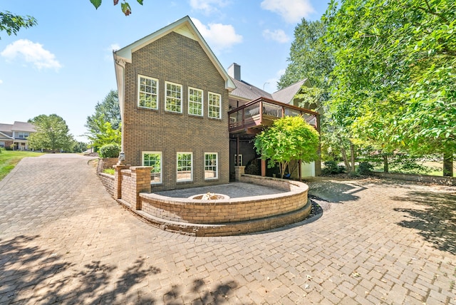 view of front of house with an outdoor fire pit, a deck, and a patio