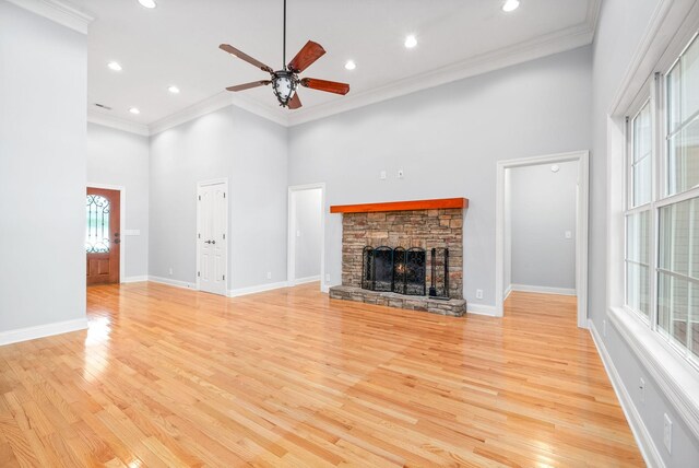 unfurnished living room with light hardwood / wood-style flooring, a stone fireplace, and a healthy amount of sunlight