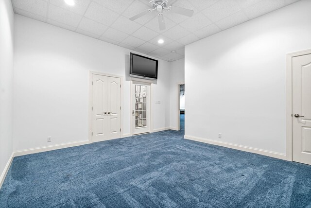 unfurnished bedroom featuring a drop ceiling, ceiling fan, and carpet flooring