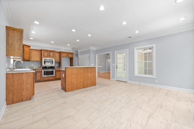 kitchen featuring ornamental molding, stainless steel appliances, a center island with sink, and sink