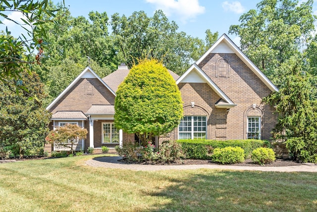 view of front of house with a front yard, brick siding, and a chimney