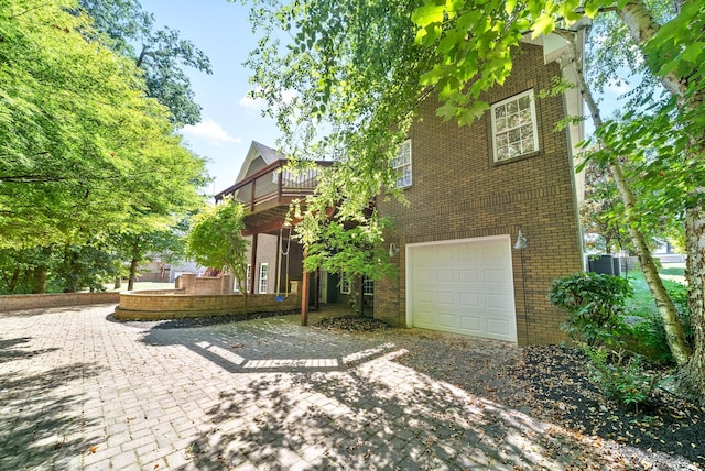 rear view of house with brick siding, a balcony, and an attached garage