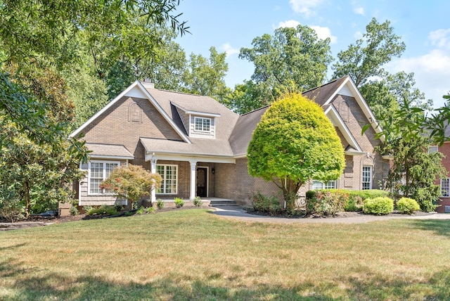 view of front facade with brick siding, a chimney, and a front lawn