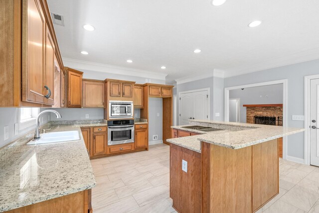 kitchen with a kitchen island, light stone countertops, stainless steel appliances, ornamental molding, and sink