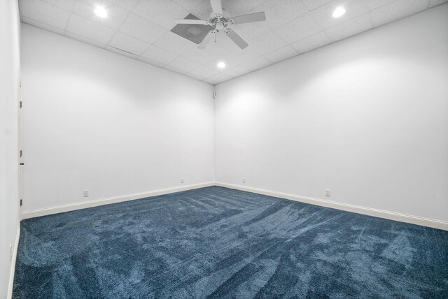 carpeted empty room featuring ceiling fan and a drop ceiling