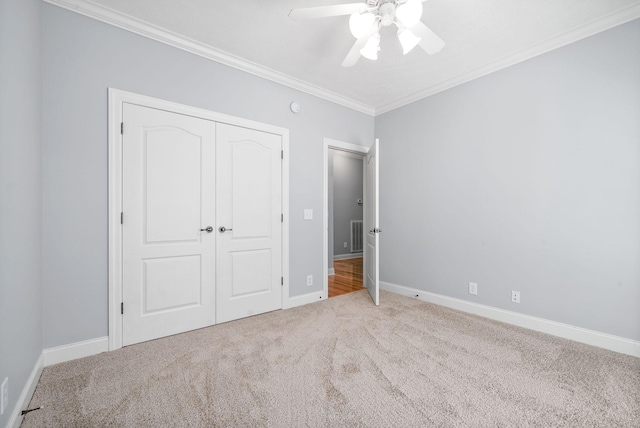 unfurnished bedroom featuring carpet floors, a closet, crown molding, and baseboards