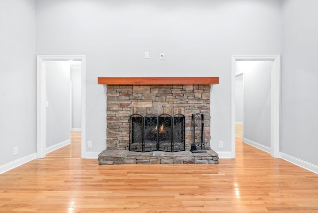 room details with a stone fireplace, baseboards, and wood finished floors