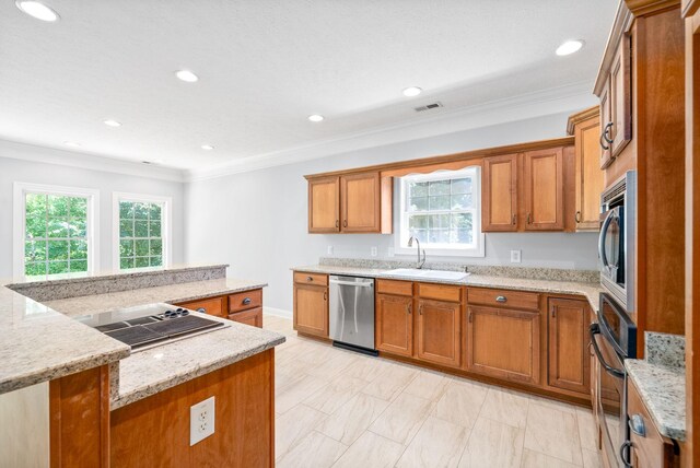 kitchen with a kitchen island, crown molding, stainless steel appliances, sink, and light stone counters