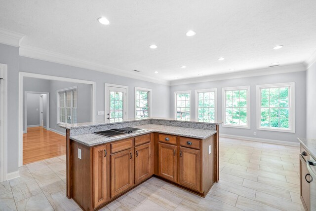 kitchen with crown molding, stainless steel gas cooktop, a healthy amount of sunlight, and light stone counters