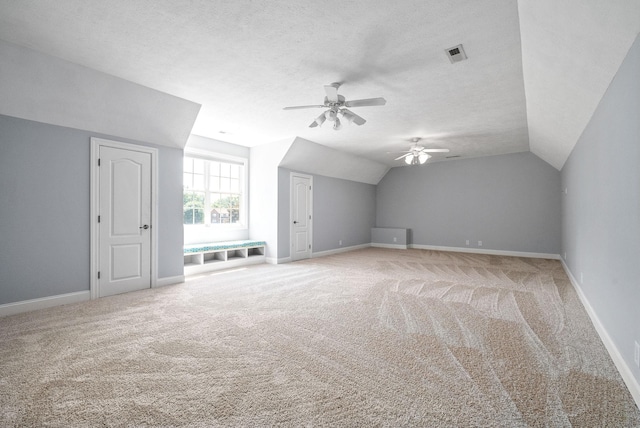 bonus room with carpet, lofted ceiling, visible vents, a textured ceiling, and baseboards