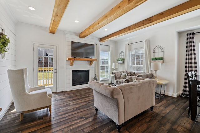 living room with dark wood-type flooring, beamed ceiling, and a large fireplace