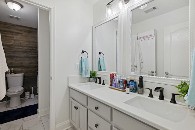 bathroom featuring vanity, toilet, and wood walls