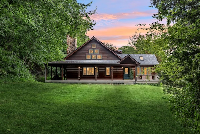 back of house with a shingled roof, a chimney, a porch, and a yard