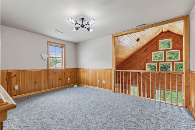 empty room with a wainscoted wall, carpet flooring, visible vents, and wooden walls