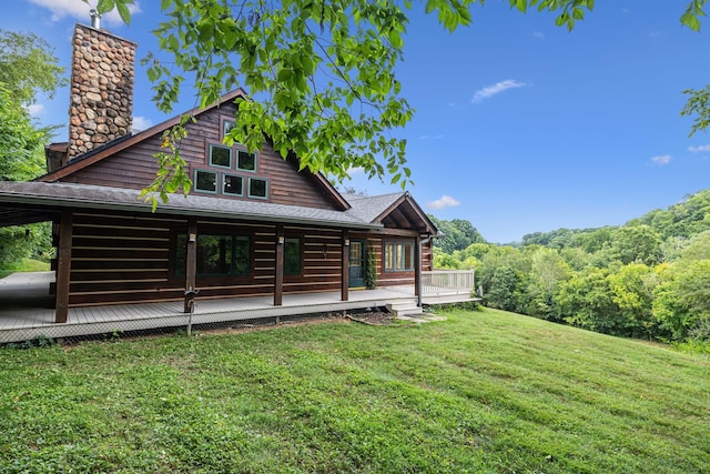 rear view of property featuring a deck, a yard, and a chimney