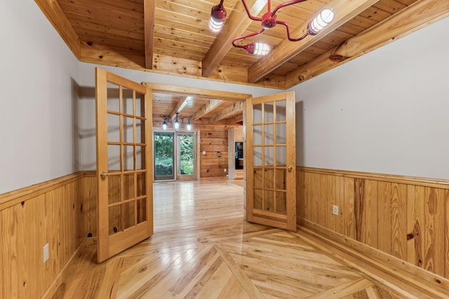 unfurnished room with wainscoting, wood ceiling, beamed ceiling, french doors, and wood walls