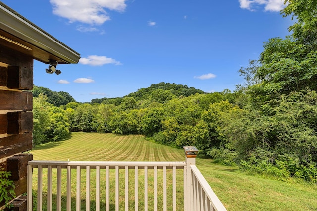 view of yard with a balcony and a wooded view