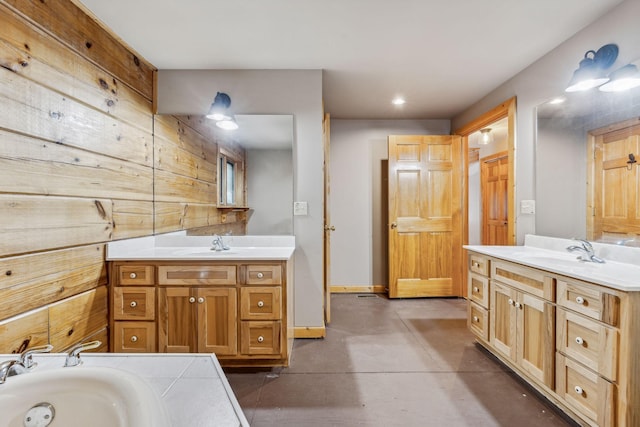 full bath with two vanities, a sink, and baseboards