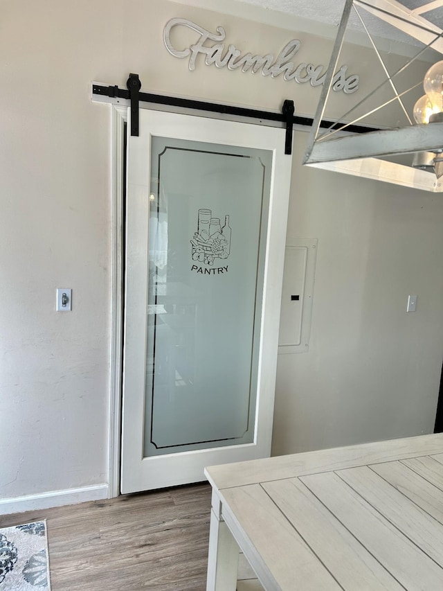 interior space featuring a barn door, electric panel, and wood finished floors