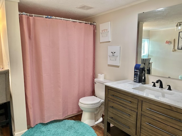 bathroom featuring a textured ceiling, toilet, visible vents, vanity, and ornamental molding