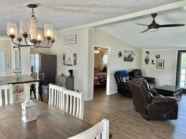 dining space with a textured ceiling, ceiling fan with notable chandelier, wood finished floors, vaulted ceiling, and crown molding