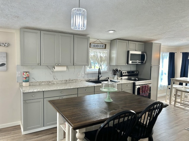 kitchen featuring appliances with stainless steel finishes, gray cabinets, a sink, and light wood-style flooring