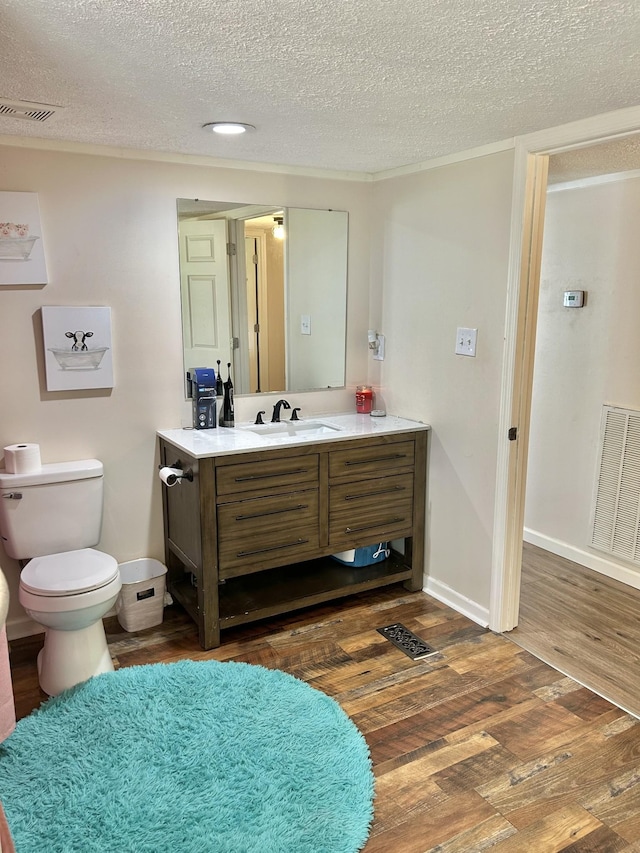 bathroom with baseboards, visible vents, toilet, wood finished floors, and vanity