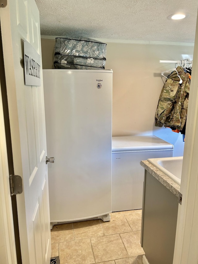 clothes washing area with a textured ceiling and laundry area