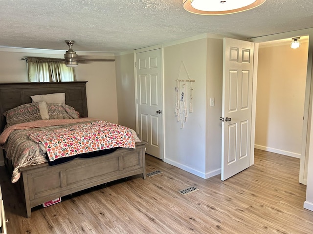 bedroom featuring light wood finished floors, baseboards, and a textured ceiling