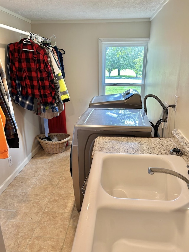 laundry area featuring ornamental molding, washer and dryer, a textured ceiling, and baseboards