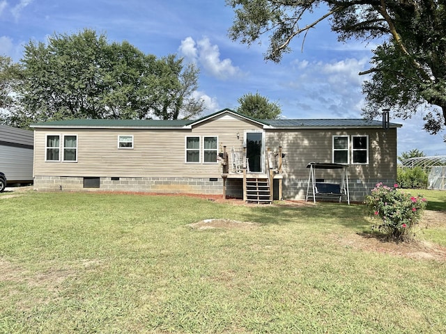 rear view of property featuring crawl space, metal roof, and a lawn