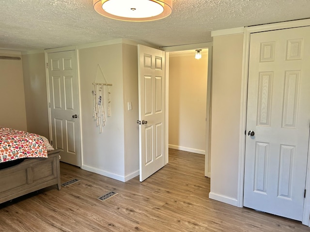 bedroom featuring light wood-style flooring, baseboards, and a textured ceiling