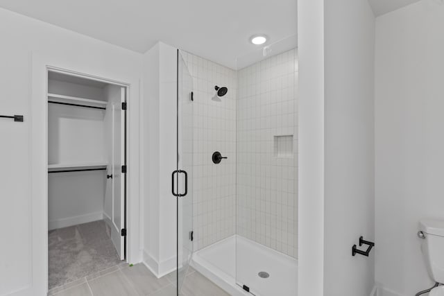 bathroom with toilet, tile patterned flooring, and a shower with door