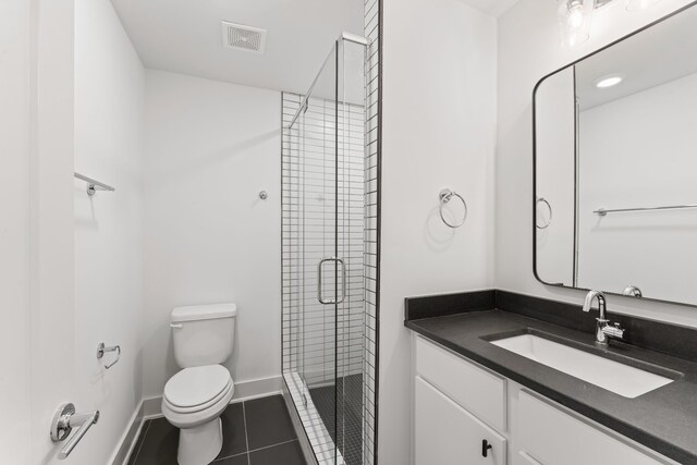 bathroom featuring tile patterned flooring, vanity, toilet, and a shower with door