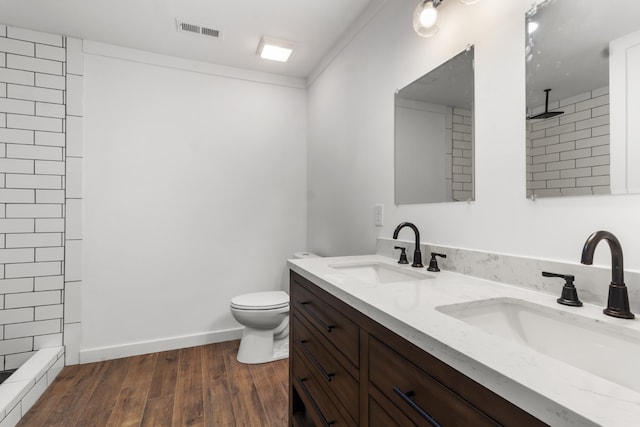 bathroom with a tile shower, vanity, hardwood / wood-style floors, and toilet