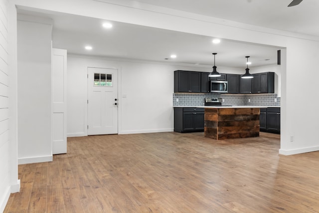 kitchen featuring stainless steel appliances, a center island, light hardwood / wood-style flooring, decorative light fixtures, and ornamental molding