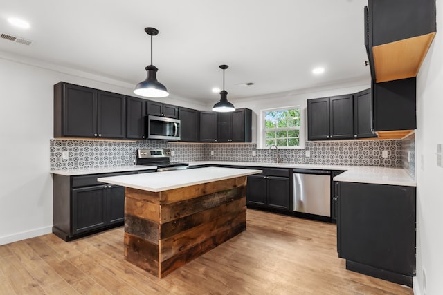 kitchen with light wood-type flooring, sink, hanging light fixtures, stainless steel appliances, and backsplash