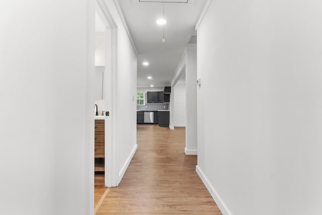 corridor with sink, crown molding, and light hardwood / wood-style floors