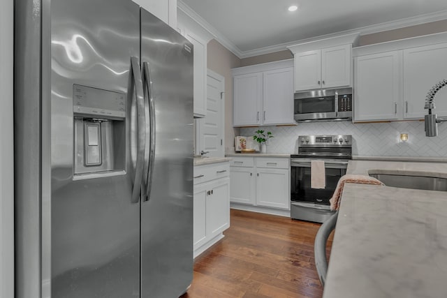 kitchen with white cabinets, wood-type flooring, stainless steel appliances, and light stone countertops