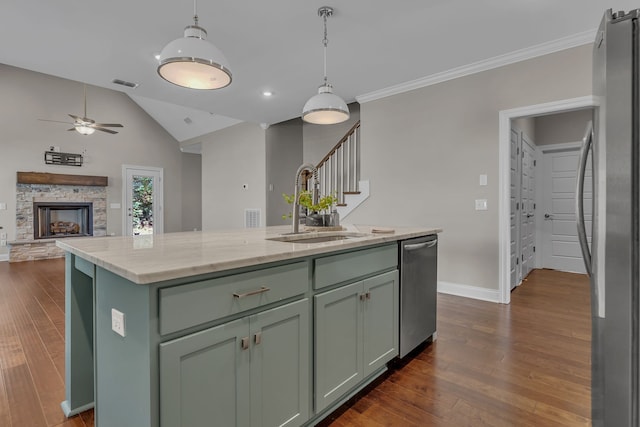 kitchen featuring dark wood-type flooring, sink, a stone fireplace, and a kitchen island with sink