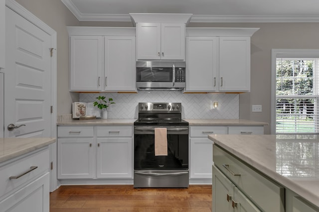 kitchen with light stone counters, a wealth of natural light, stainless steel appliances, and light hardwood / wood-style floors