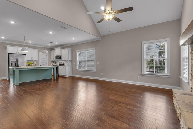 unfurnished living room featuring dark wood-type flooring, vaulted ceiling, ornamental molding, and ceiling fan